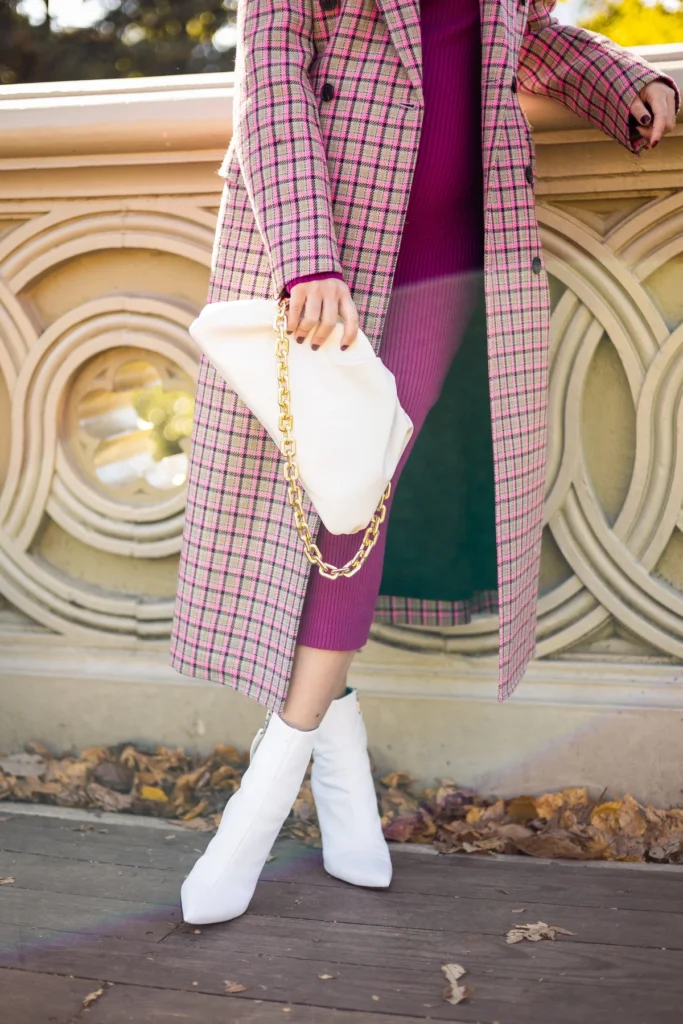 Waist-down view of magenta sweater dress with white boots