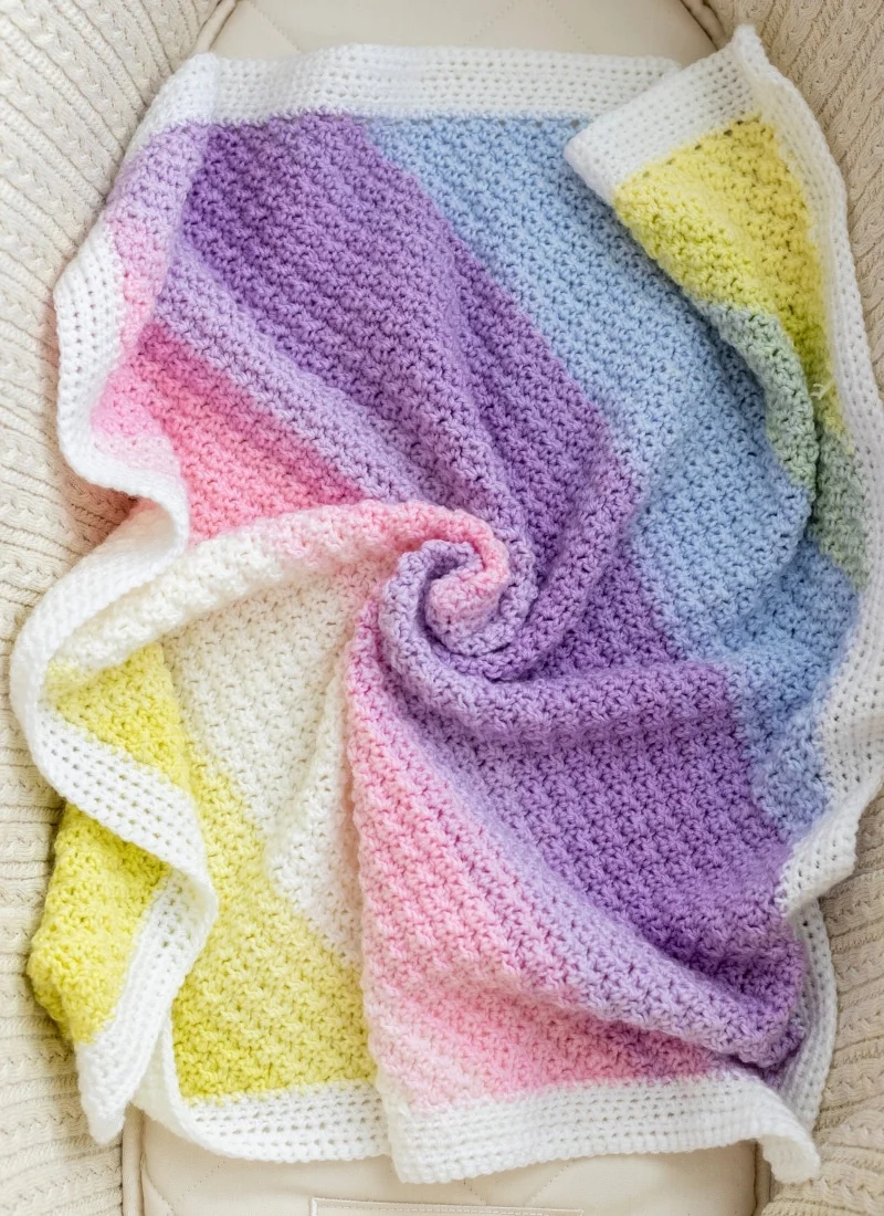 Corner-to-corner crochet blanket with white border on textured surface