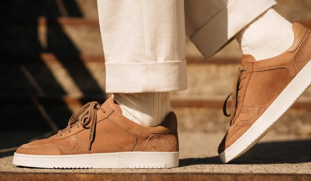 Tan suede quiet luxury sneakers worn in a street setting