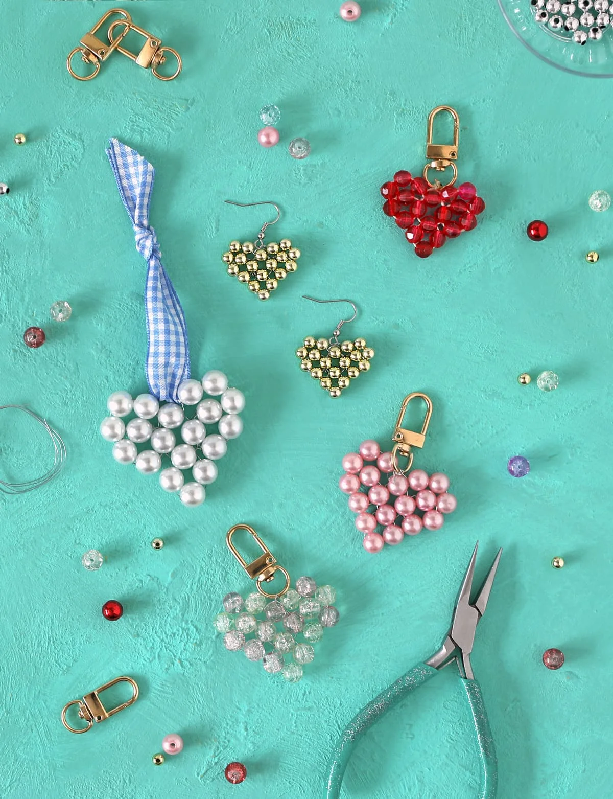 Beaded heart charms and jewelry findings arranged on a turquoise background