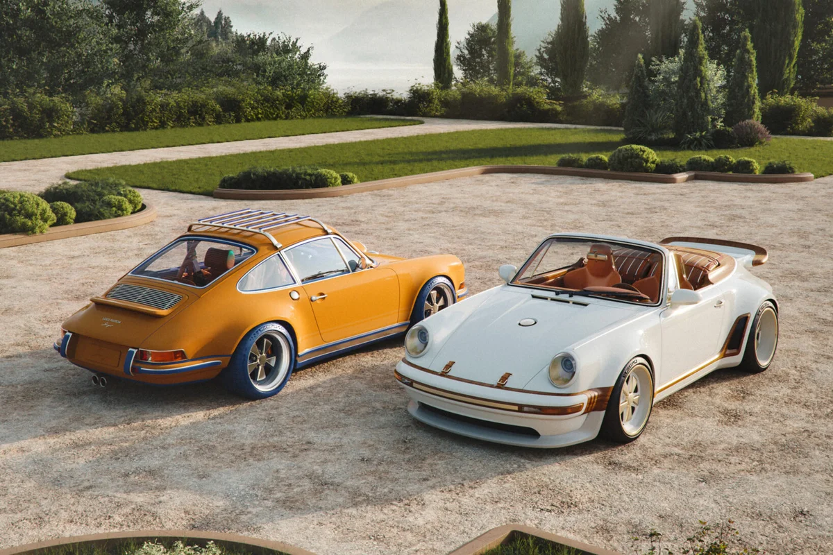 Two Singer-reimagined Porsche 911s parked in a garden setting