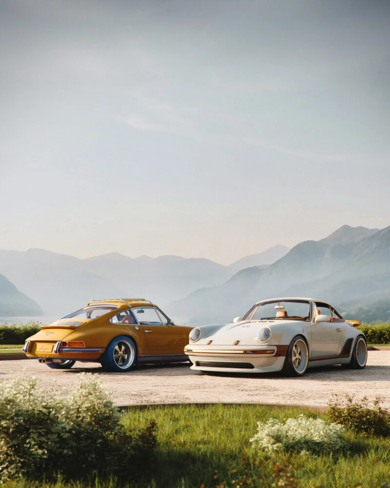 Two vintage Porsche 911s parked on a gravel road with mountains behind