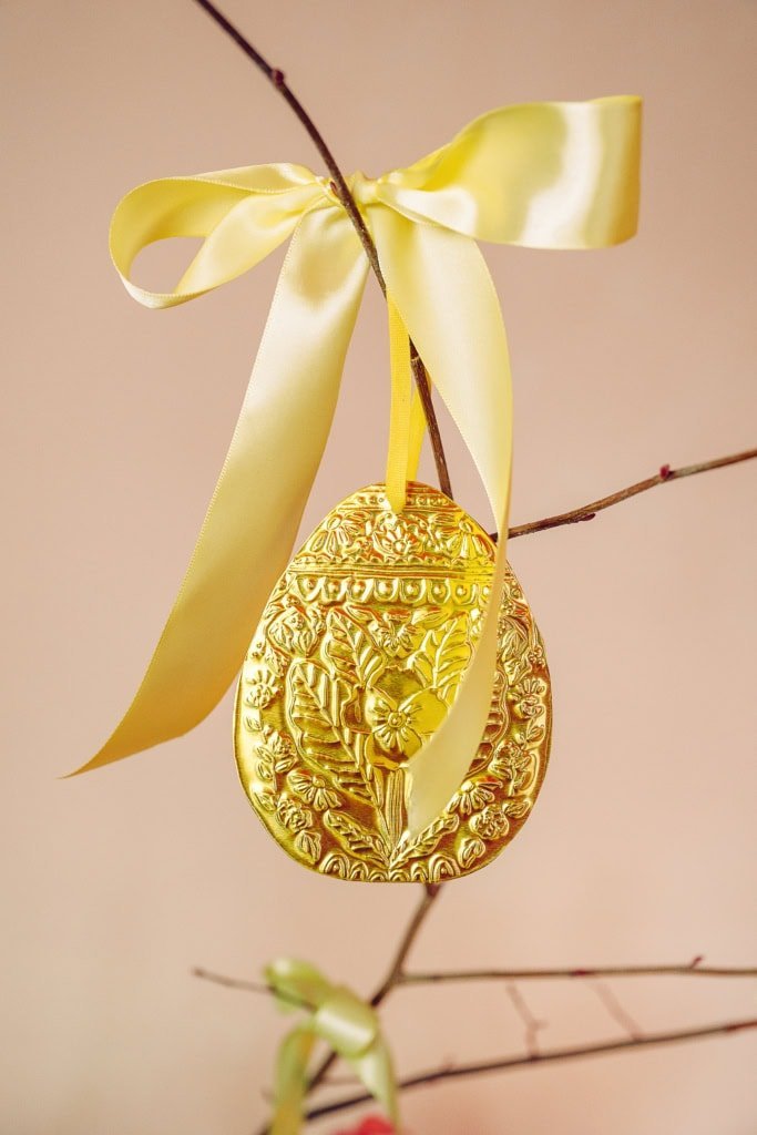 Flat-lay of tin embossed Easter ornaments in pastel ribbon colors