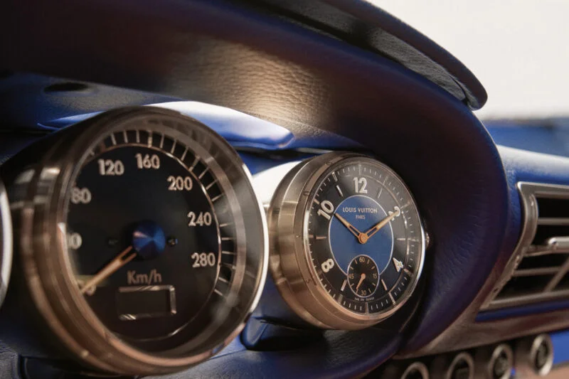 Close-up of a car dashboard featuring a Louis Vuitton clock and gauges