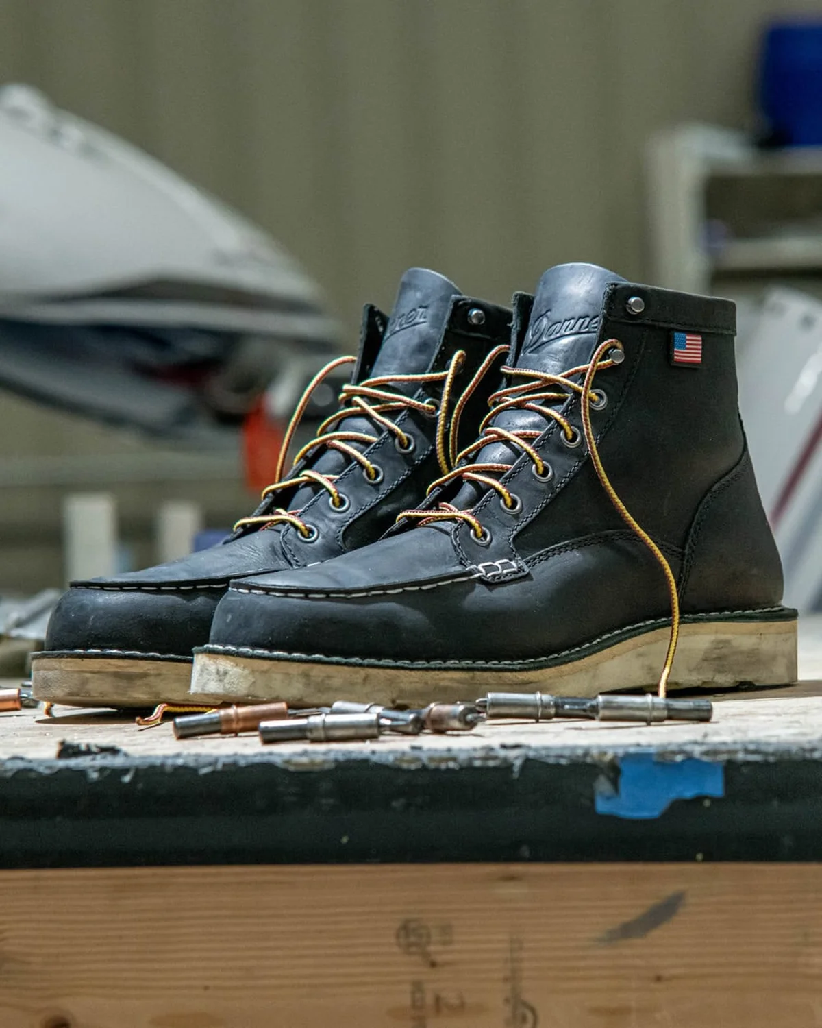 Well-used Danner leather work boots resting on a weathered wooden bench