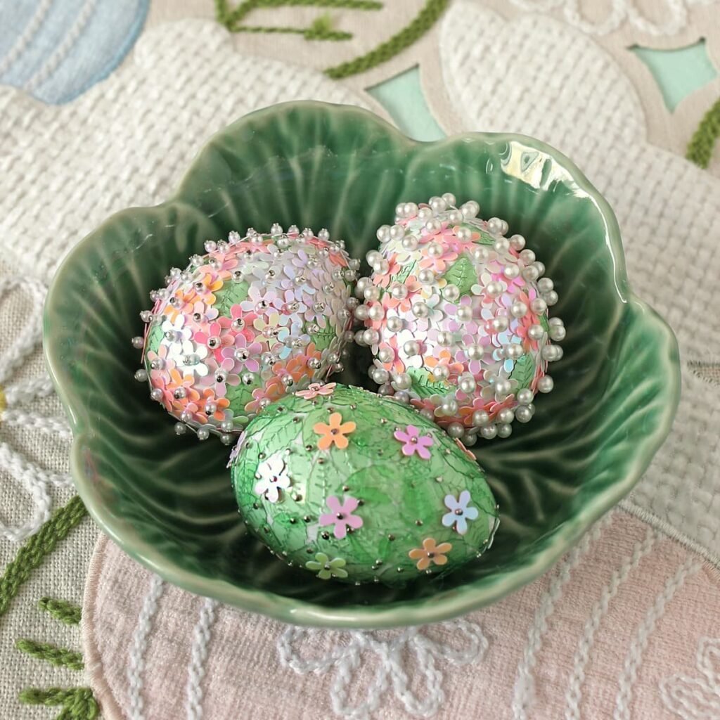 Sequined and beaded Easter eggs arranged in a scalloped ceramic bowl